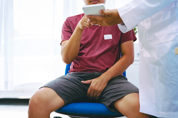 A man suffering from urinary tract infections visits a doctor at the examination table in a...