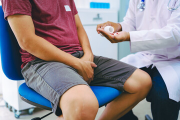 A man suffering from urinary tract infections visits a doctor at the examination table in a...