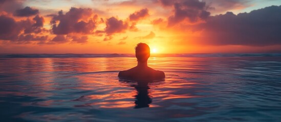 Silhouette of a person in the ocean at sunset.