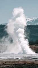 Majestic Geyser Eruption in Scenic Landscape with Snow-Capped Mountains and Clear Blue Sky in the Background: Nature's Hydrothermal Phenomenon and Scenic Vista