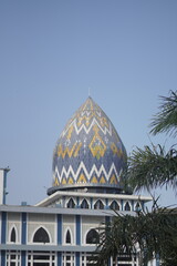 The red and white yellow dome of the mosque with a blue sky background