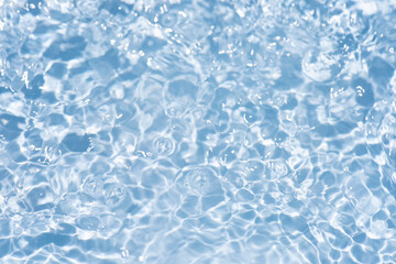 Obraz premium Blue water with ripples on the surface. Defocus blurred transparent blue colored clear calm water surface texture with splashes and bubbles. Water waves with shining pattern texture background.