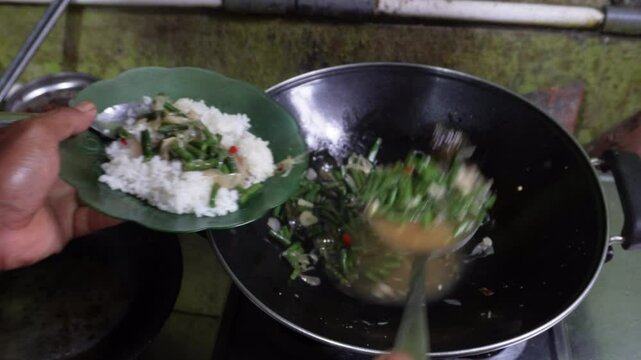 Oseng or tumis buncis daun salam bawang putih is served to a plate, fresh from wok cook. The saut&eacute;ed green beans, garlic, and bay leaves, sizzling. Indonesian javenese dish. Homemade delicious flavor