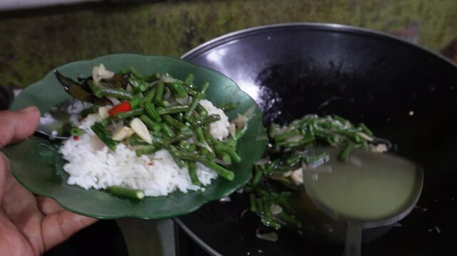 Oseng or tumis buncis daun salam bawang putih is served to a plate, fresh from wok cook. The saut&eacute;ed green beans, garlic, and bay leaves, sizzling. Indonesian javenese dish. Homemade delicious flavor