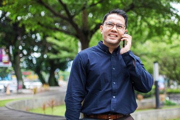 Portrait Of Man In Formal Suit Calling Using Mobile Phone While Standing on Park