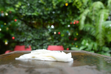 Wipe up the water on the table with paper towels, Water spilled on the dark brown wood and white tissue paper that wet after wipe, dirty surface of plywood table