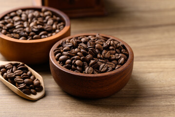 Roasted coffee beans in bowl on wooden table, Arabica coffee