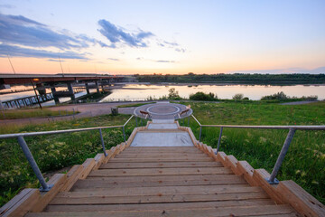 Obraz premium A bridge spans a river with a beautiful sunset in the background