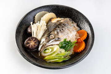 Salmon head in soya soup steamed with ingredient in Japanese style food. On a white background