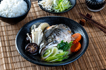 Salmon head in soya soup steamed with ingredient in Japanese style food.