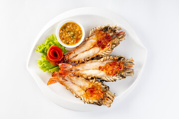 Grilled giant river prawn served on a plate with Thai seafood sauce. On a white background