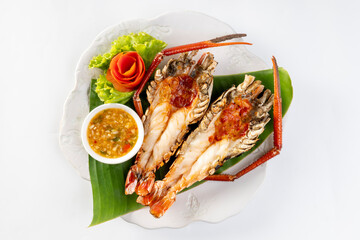 Grilled giant river prawn served on a plate with Thai seafood sauce. On a white background