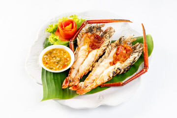 Grilled giant river prawn served on a plate with Thai seafood sauce. On a white background