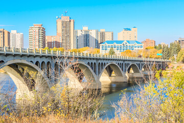 Naklejka premium A bridge spans a river in a city with tall buildings in the background