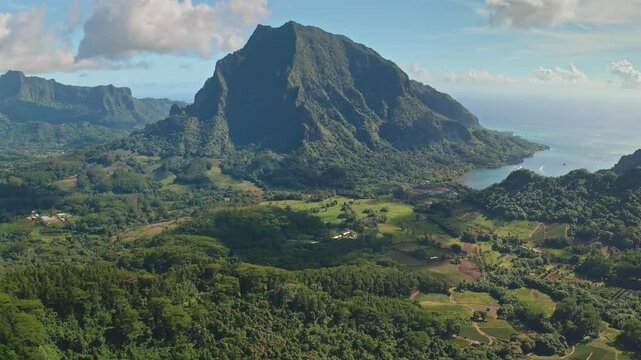 Aerial view revealing stunning beauty of Moorea, French Polynesia, with mount Rotui towering over green hills landscapes and tranquil turquoise water. Wild travel destination, remote nature paradise