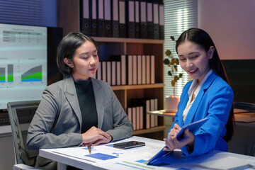 Two young businesswomen analyzing financial charts and data during a productive meeting in a modern office