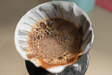 Close-up of coffee grounds blooming in a V60 dripper with bubbles forming during pour-over brewing. Highlights fresh coffee extraction, manual brewing, and the aromatic V60 coffee-making process.