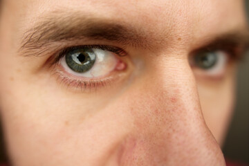 Man looks curiously into camera. Intense gaze with gray eyes. Male face with focused expression