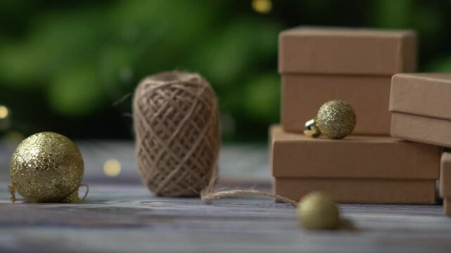 Holiday decor. Packing holiday gifts. Gift boxes and natural twine and Christmas gold balls on a Christmas tree background and bokeh. Moving focus across items