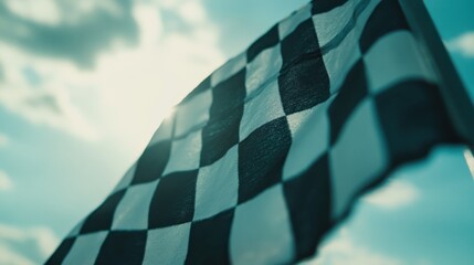 A close-up of a checkered flag waving against a bright sky, symbolizing racing and competition.