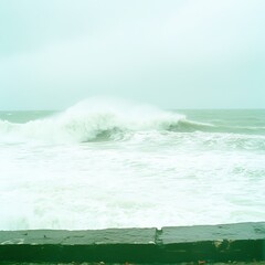 Fototapeta premium Ocean Wave Crashing Against Seawall on Cloudy Day