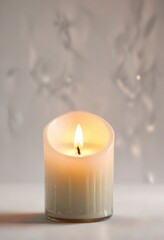 Soft warm light of a candle flame on a white background, gentle illumination, simple elegance