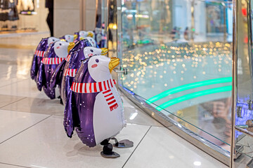 funny inflatable toy penguins in scarves in the interior of the supermarket. Preparation for...