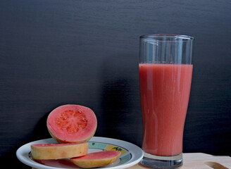 Refreshing guava smoothie in a tall glass paired with a plate of sliced guava, vibrant colors and fresh tropical vibes, perfect for healthy living concepts