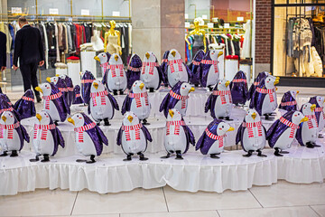 funny inflatable toy penguins in scarves in the interior of the supermarket. Preparation for...