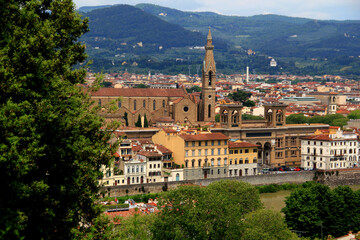 Aerial view of the Arno River embankment with the National Library of Florence building and the Basilica di Santa Croce di Firenze against the backdrop of green hills in Florence, Italy