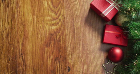 Image of holly text over christmas gifts and decorations on wooden surface with copy space