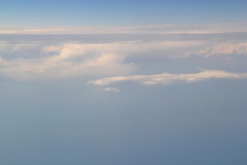 Photo of the gradient blue sky with white clouds from the porthole of the plane