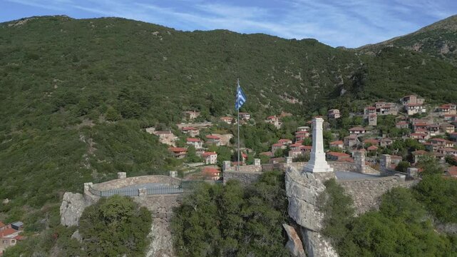 A drone captures the stunning view of the monument on the front hill, with the traditional village of Stemnitsa revealed in the background, nestled among lush greenery and timeless charm