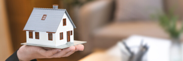 Close up real estate agent holding small house model, Home loan