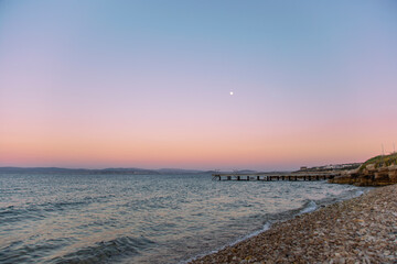 Beautiful landscape of pink sunset with moon at Aegean sea