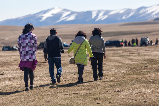 Group walking in a field with snowy mountains in the background.