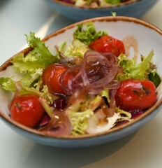 Salad with cherry tomatoes, onions and lettuce in a blue bowl