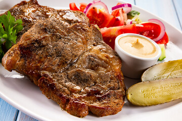Roasted chuck steak with mayonnaise and fresh vegetables on wooden table