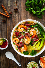 Shrimp and beef Pho soup - Vietnamese soup with shrimps and raw beef slices on wooden table	
