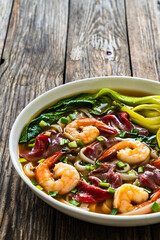 Shrimp and beef Pho soup - Vietnamese soup with shrimps and raw beef slices on wooden table	
