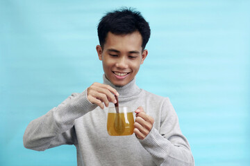 Young Asian man busy stirring herbal tea with wooden spoon
