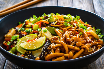 Asian style stir fried vegetables and noodles on wooden table
