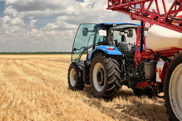 Obraz premium Rear view of tractor with trailer agricultural equipment for spraying fertilizers or water on the fields. Start tillage after harvest.
