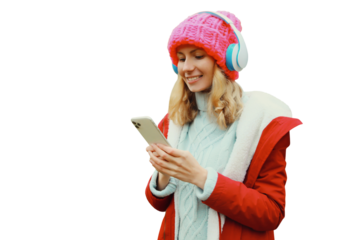 Happy young woman with phone listening to music in headphones in winter hat isolated on white