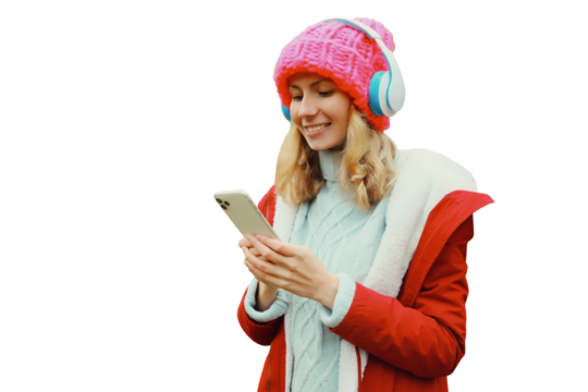 Happy young woman with phone listening to music in headphones in winter hat isolated on white
