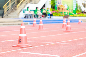 Orange traffic cones on red running track, marking lanes for sports event. vibrant colors create lively atmosphere, perfect for competitions and athletic activities