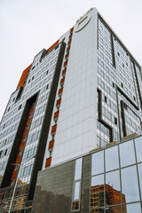 Obraz premium A sleek high-rise building in Irkutsk reflects the cloudy sky, showcasing modern design and urban living.