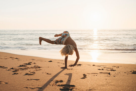 Young boy doing cartwheels at beach sunset in Spain