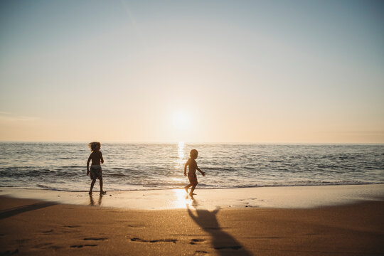Young kids running at beach during sunset in Spain