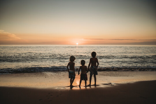 Children standing at beach watching stunning sunset in Spain